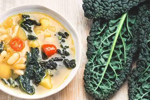 Zuppa cremosa con fagioli, pomodorini e cavolo nero. Ideale per cavolo nero ricette veloci e salutari.