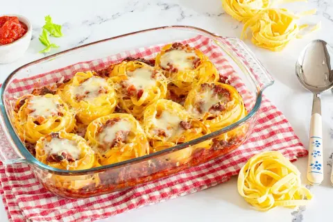 Nidi di tagliatelle al forno con ragù e formaggio fuso, pronti per essere gustati.