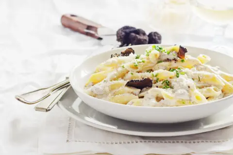 Penne cremose con funghi e tartufo nero, un piatto di pasta alla norcina che invita alla degustazione.