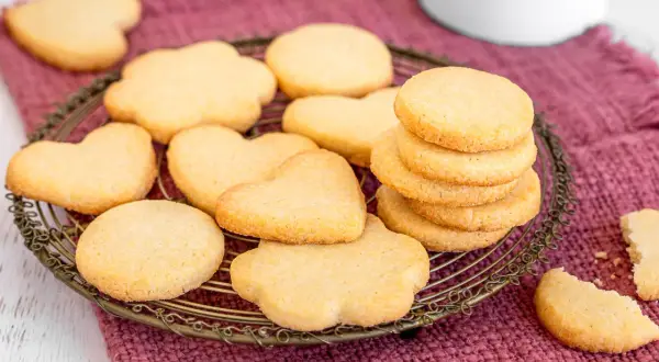 Biscotti classici a forma di cuore e fiore, impilati su una gratella dorata, pronti per essere gustati.