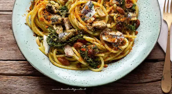 Un piatto invitante di pasta con le sarde, condita con erbe aromatiche, pinoli e pangrattato tostato.