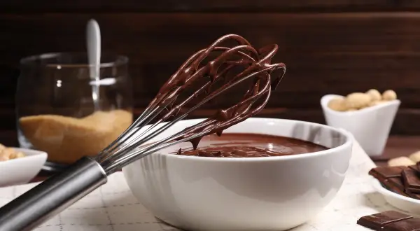 Frusta ricoperta di golosa crema pasticcera al cioccolato, pronta per essere gustata.