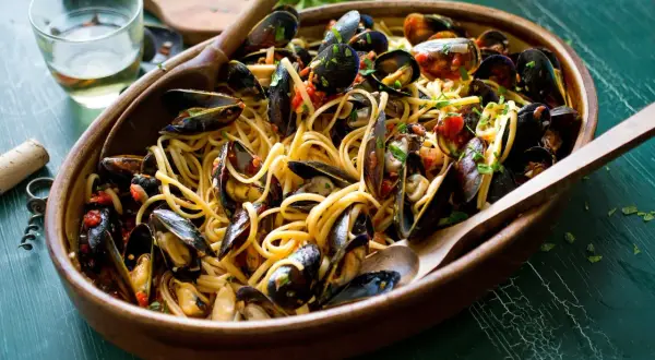 Un invitante piatto di spaghetti con le cozze, condito con pomodoro e prezzemolo, pronto per essere gustato.