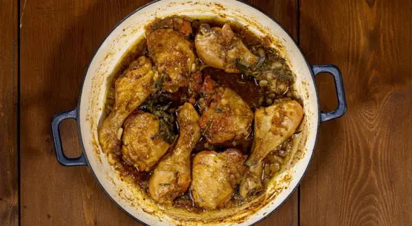 Succulento pollo alla birra cotto in una casseruola, con pezzi dorati e succosi immersi in un sugo aromatico con erbe.