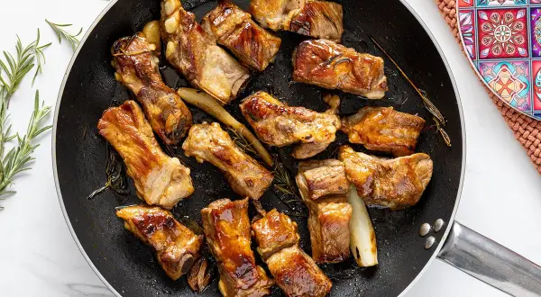 Costine di maiale in padella, dorate e succulente, profumate al rosmarino. Un piatto invitante pronto per essere gustato.