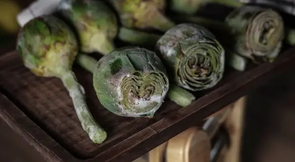 Carciofi freschi su un tagliere di legno, pronti per imparare come congelare i carciofi e conservarli per l'inverno.