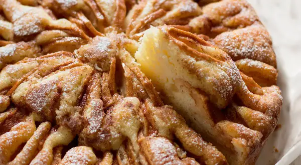 Una torta di mele umida e soffice, con un impasto dorato e mele caramellate, spolverata di zucchero a velo.