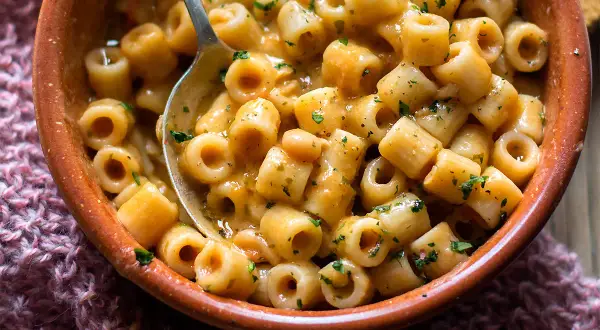 Un piatto fumante di pasta e fagioli, la ricetta della nonna, con ditalini e fagioli in un sugo cremoso, guarnito con prezzemolo tritato.
