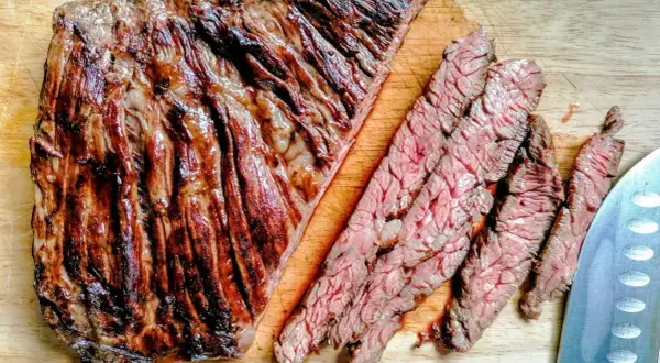 Diaframma di manzo grigliato, tagliato a fette sottili su un tagliere di legno. La carne è succulenta e ben cotta, con striature di grasso che la rendono ancora più invitante.