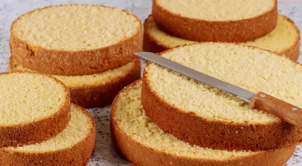 Dischi di pan di spagna pronti per essere farciti. Una lama affilata è appoggiata su uno strato, invitando a creare dolci delizie.