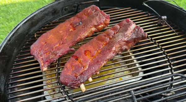 Costine al forno succulente e speziate che cuociono lentamente su una griglia, pronte per essere gustate.