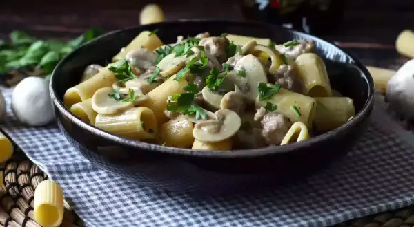 Piatto fumante di pasta funghi e salsiccia, guarnito con prezzemolo fresco. Un classico confortante.