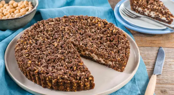 Sbriciolata ricotta e cioccolato con croccante copertura di nocciole. Una fetta invitante attende su un piattino.