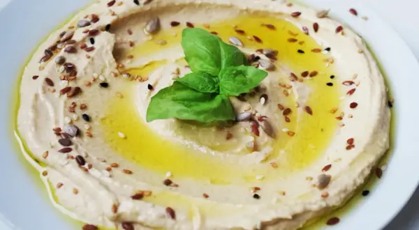 Cremoso hummus di ceci, condito con olio d'oliva, semi misti e una foglia di basilico fresco.