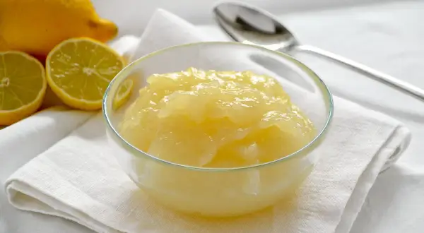 Una ciotola di cremosa crema di limoncello, con limoni freschi affettati accanto.