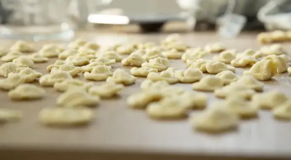 Orecchiette fatte in casa, pronte per essere cucinate. Un mare di pasta fresca su un tagliere di legno.