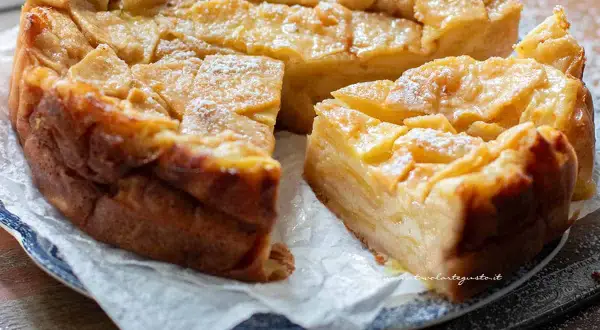 Una deliziosa torta di mele dorata, con fette di mela caramellate in superficie e una spolverata di zucchero a velo.