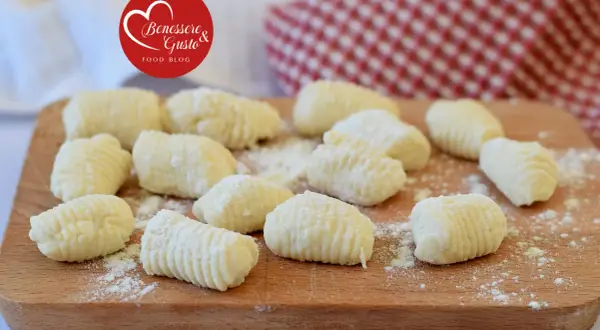 Gnocchi di ricotta freschi, pronti per essere cucinati, spolverati di farina su un tagliere di legno.