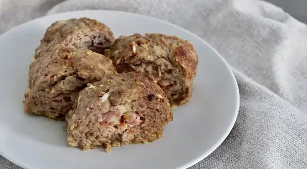 Quattro fette di polpettone al forno morbido, con ripieno di prosciutto e formaggio, servite su un piatto bianco.