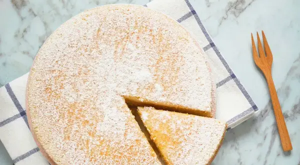 Torta 7 vasetti soffice e spolverata di zucchero a velo, pronta per essere gustata. Un pezzo è già stato tagliato.