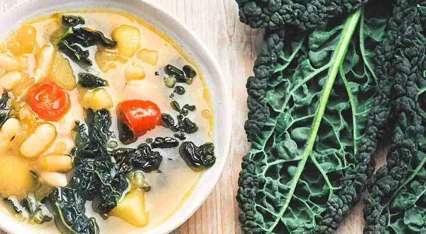 Zuppa cremosa con fagioli, pomodorini e cavolo nero. Ideale per cavolo nero ricette veloci e salutari.