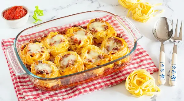 Nidi di tagliatelle al forno con ragù e formaggio fuso, pronti per essere gustati.