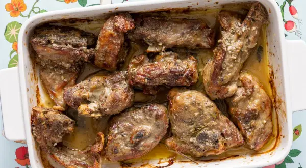 Pezzi succulenti di abbacchio alla romana cotti in teglia, con erbe aromatiche e succo saporito.