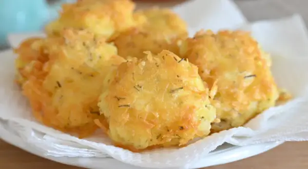 Frittelle di patate dorate e croccanti, condite con erbe aromatiche, servite su carta assorbente.
