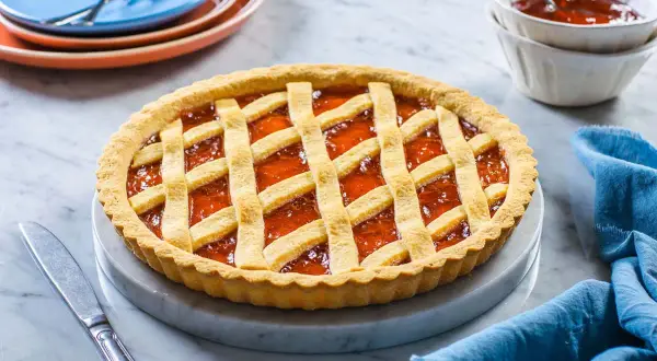 Una deliziosa crostata di marmellata con una griglia dorata di pasta frolla, pronta per essere gustata.
