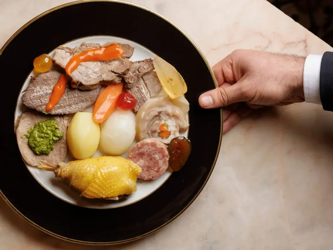 Piatto ricco con bollito di carne, pollo, salumi, verdure e salse, servito su un piatto elegante.