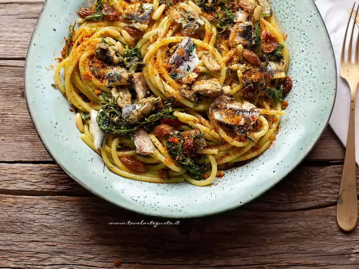 Un piatto invitante di pasta con le sarde, condita con erbe aromatiche, pinoli e pangrattato tostato.