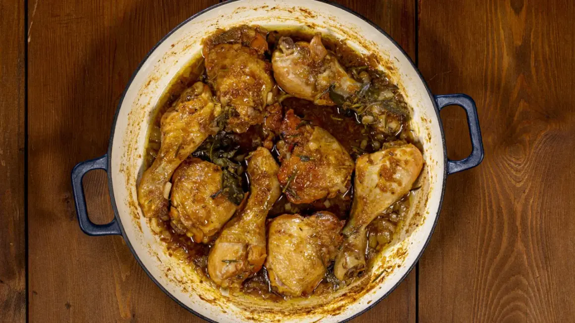 Succulento pollo alla birra cotto in una casseruola, con pezzi dorati e succosi immersi in un sugo aromatico con erbe.