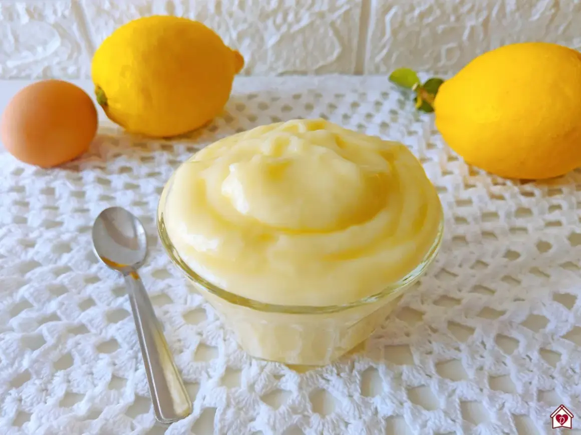Crema pasticcera al limone, soffice e profumata, pronta per essere gustata. Accanto, un uovo e limoni freschi.