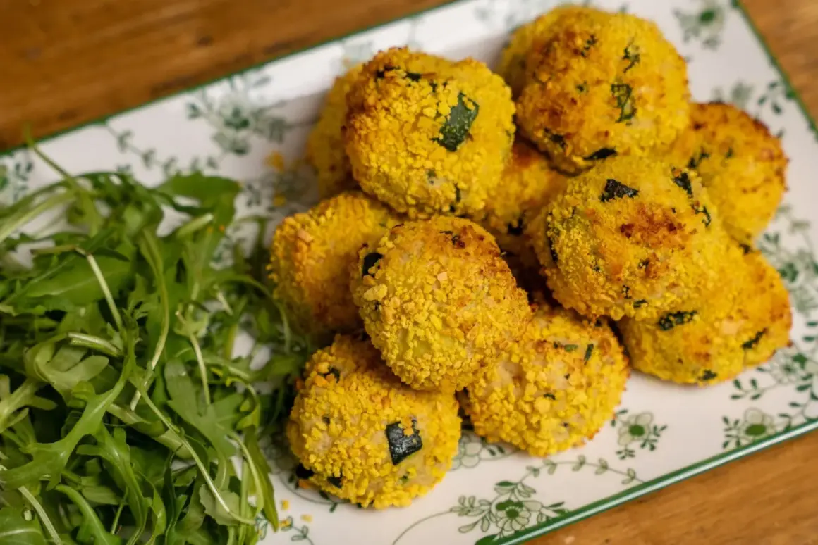 Polpette di zucchine al forno dorate e croccanti, servite su un piatto con rucola fresca.