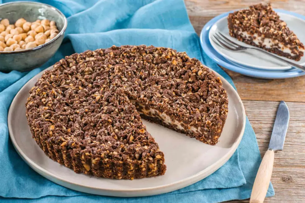 Sbriciolata ricotta e cioccolato con croccante copertura di nocciole. Una fetta invitante attende su un piattino.