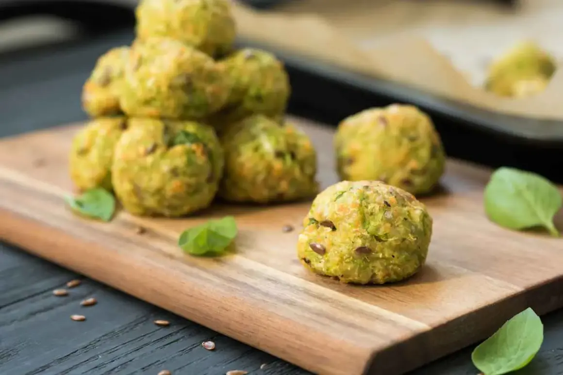 Deliziose polpette di zucchine, dorate e profumate, su un tagliere di legno con foglie di basilico fresco.