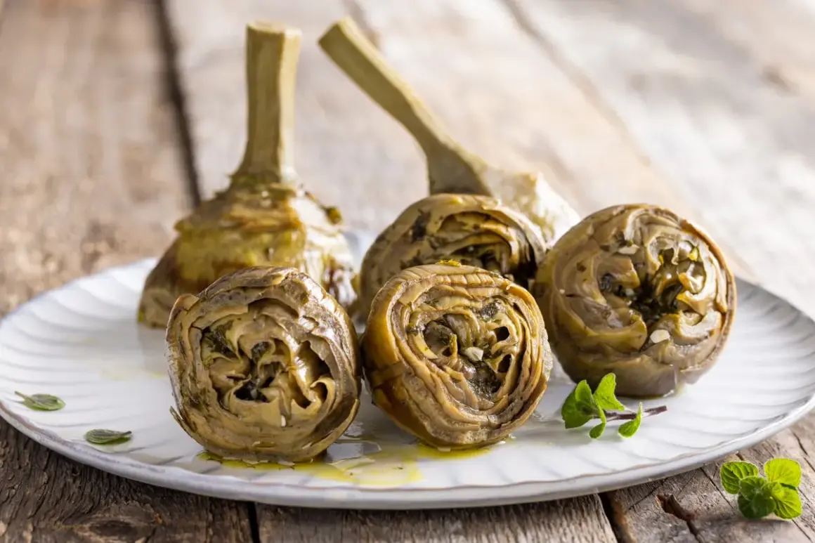 Carciofi alla romana ricetta: carciofi stufati con erbe aromatiche e aglio su un piatto bianco, pronti per essere gustati.