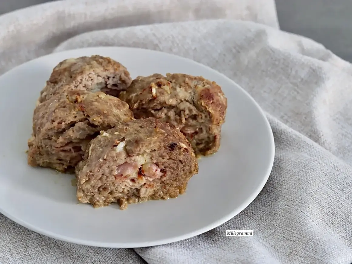 Quattro fette di polpettone al forno morbido, con ripieno di prosciutto e formaggio, servite su un piatto bianco.