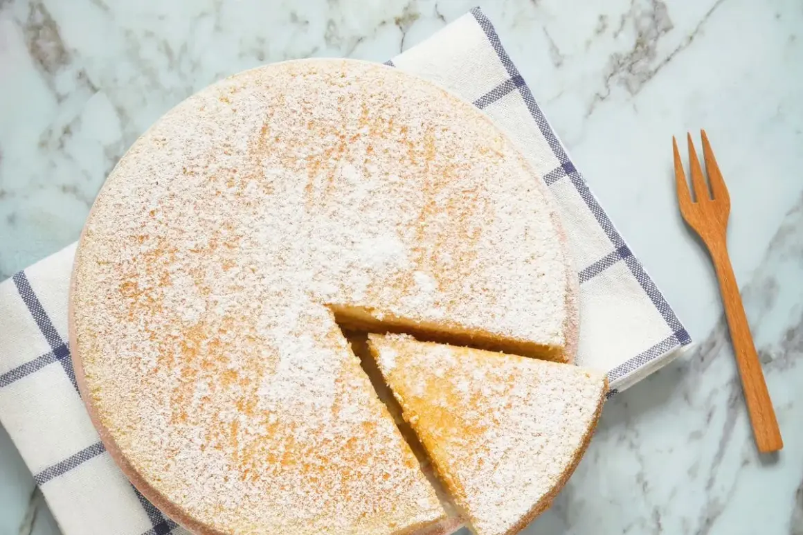Torta 7 vasetti soffice e spolverata di zucchero a velo, pronta per essere gustata. Un pezzo è già stato tagliato.