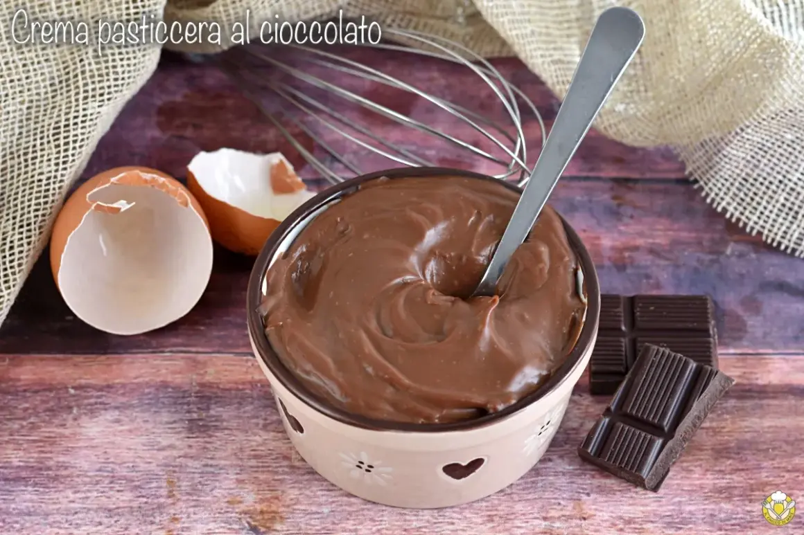 Ciotola piena di deliziosa crema al cioccolato, con gusci d'uovo, frusta e tavolette di cioccolato.