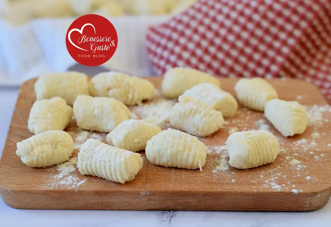 Gnocchi di ricotta freschi, pronti per essere cucinati, spolverati di farina su un tagliere di legno.