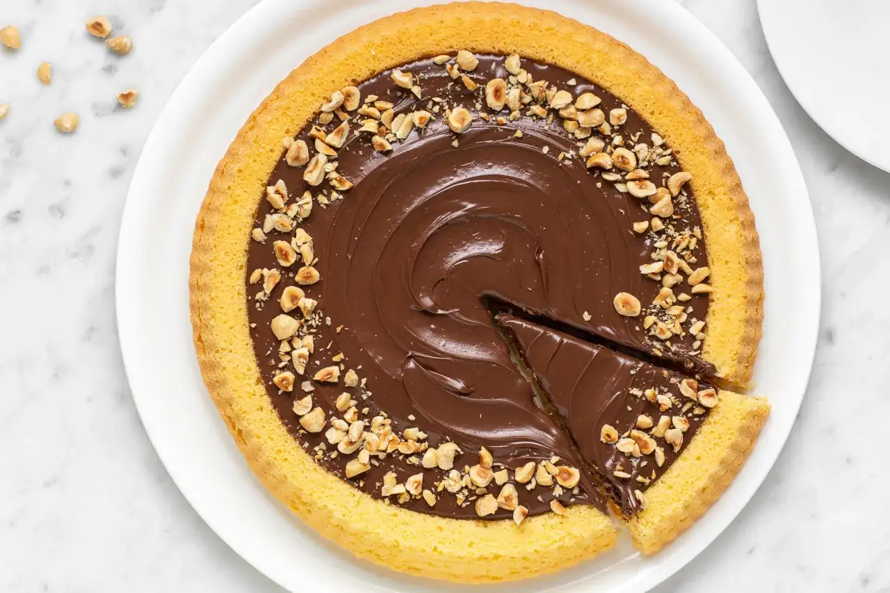 Torta con crema alla Nutella e nocciole tostate, un dolce invitante con una fetta già tagliata.