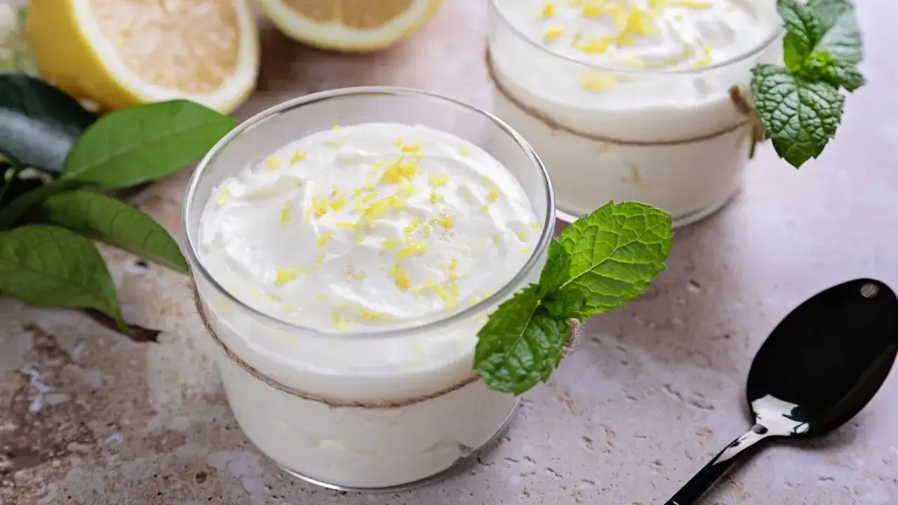 Deliziosa crema di limoncello in bicchieri decorati con menta e scorza di limone.