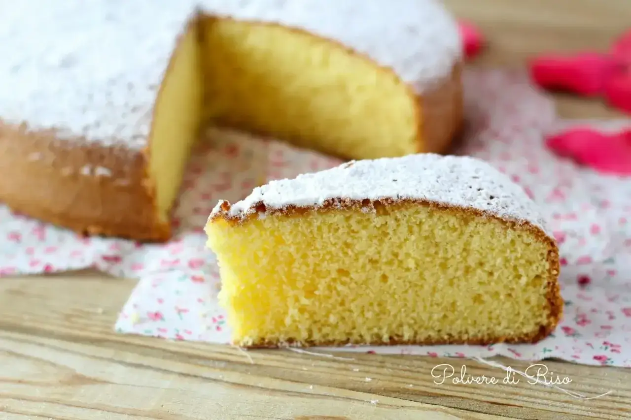 Una fetta di torta paradiso sofficissima, cosparsa di zucchero a velo, su un tovagliolo fiorato.
