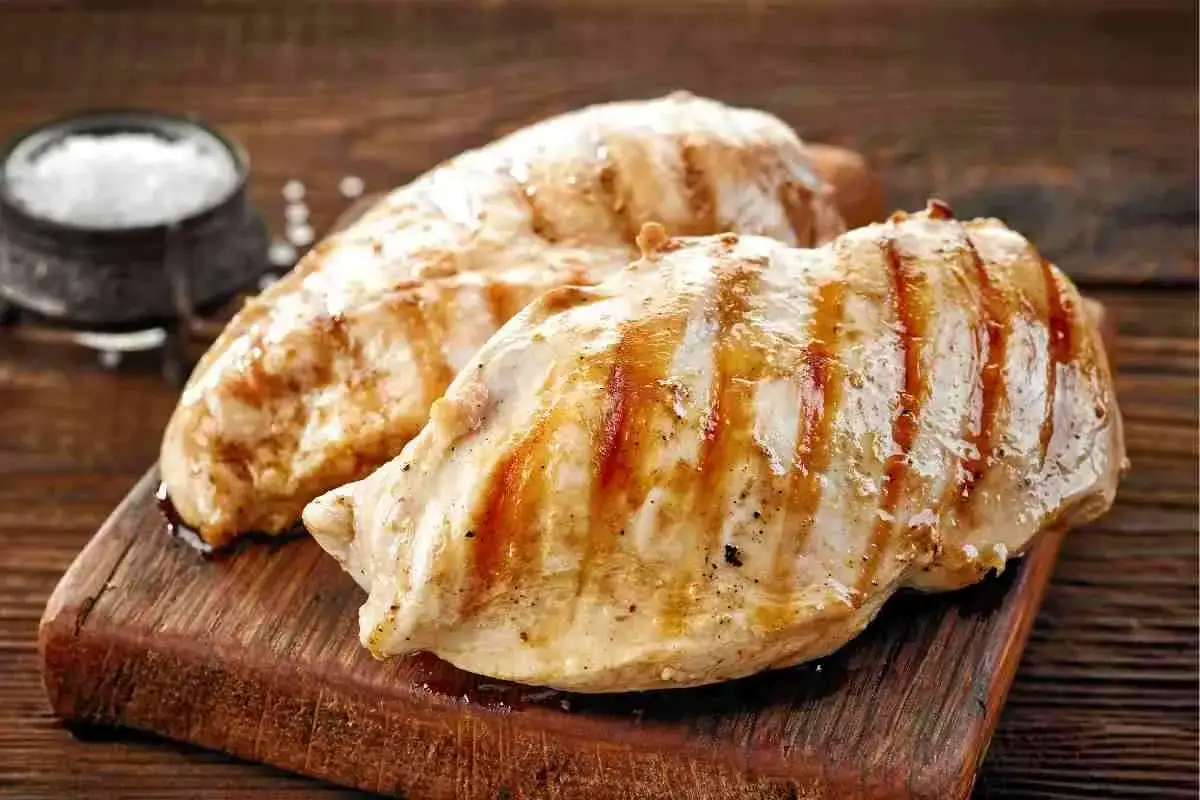 Petto di pollo grigliato su tagliere di legno, perfetto come secondi di carne da preparare in anticipo.