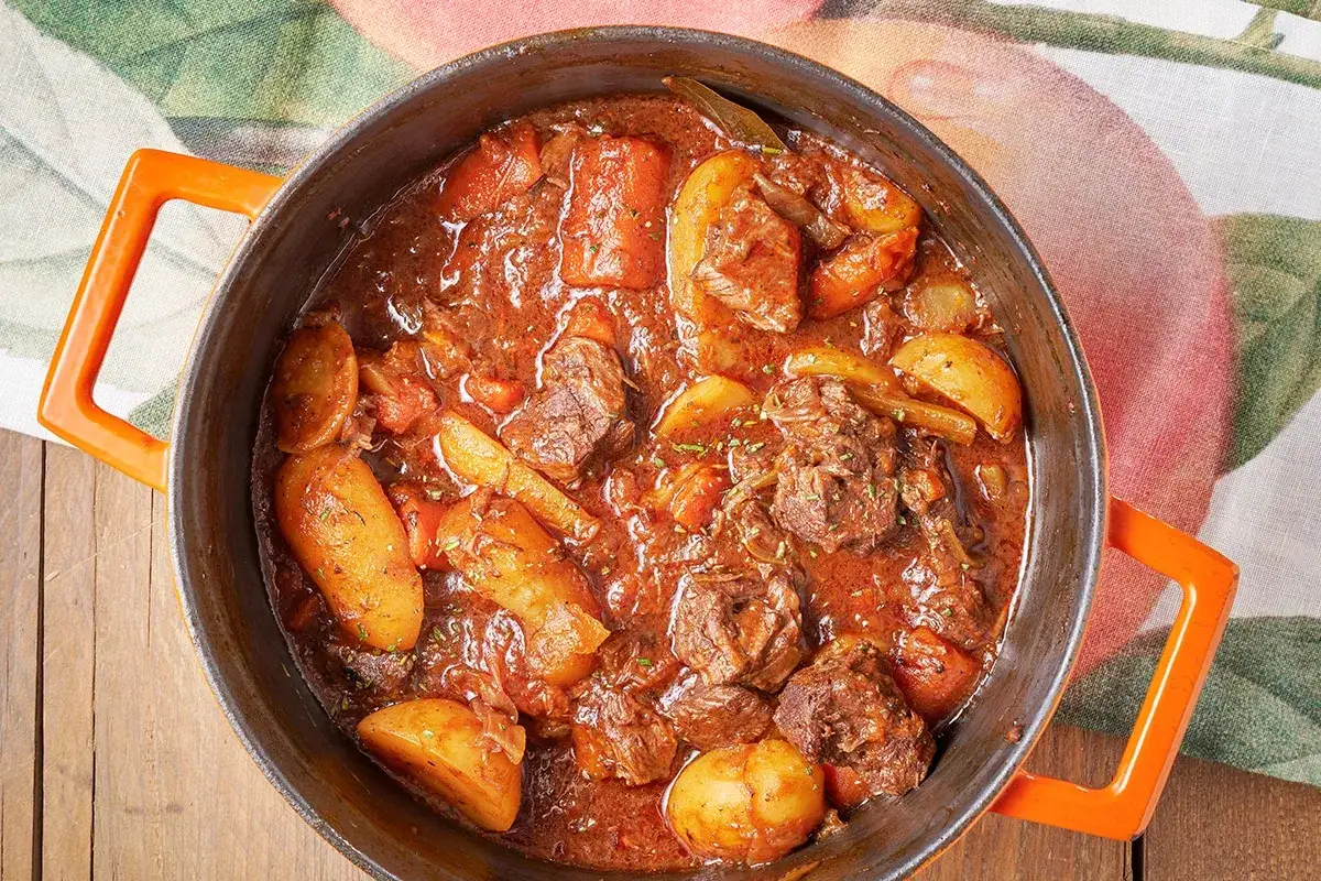 Un invitante spezzatino con patate, cotto lentamente in un tegame di ghisa, pronto per essere gustato.
