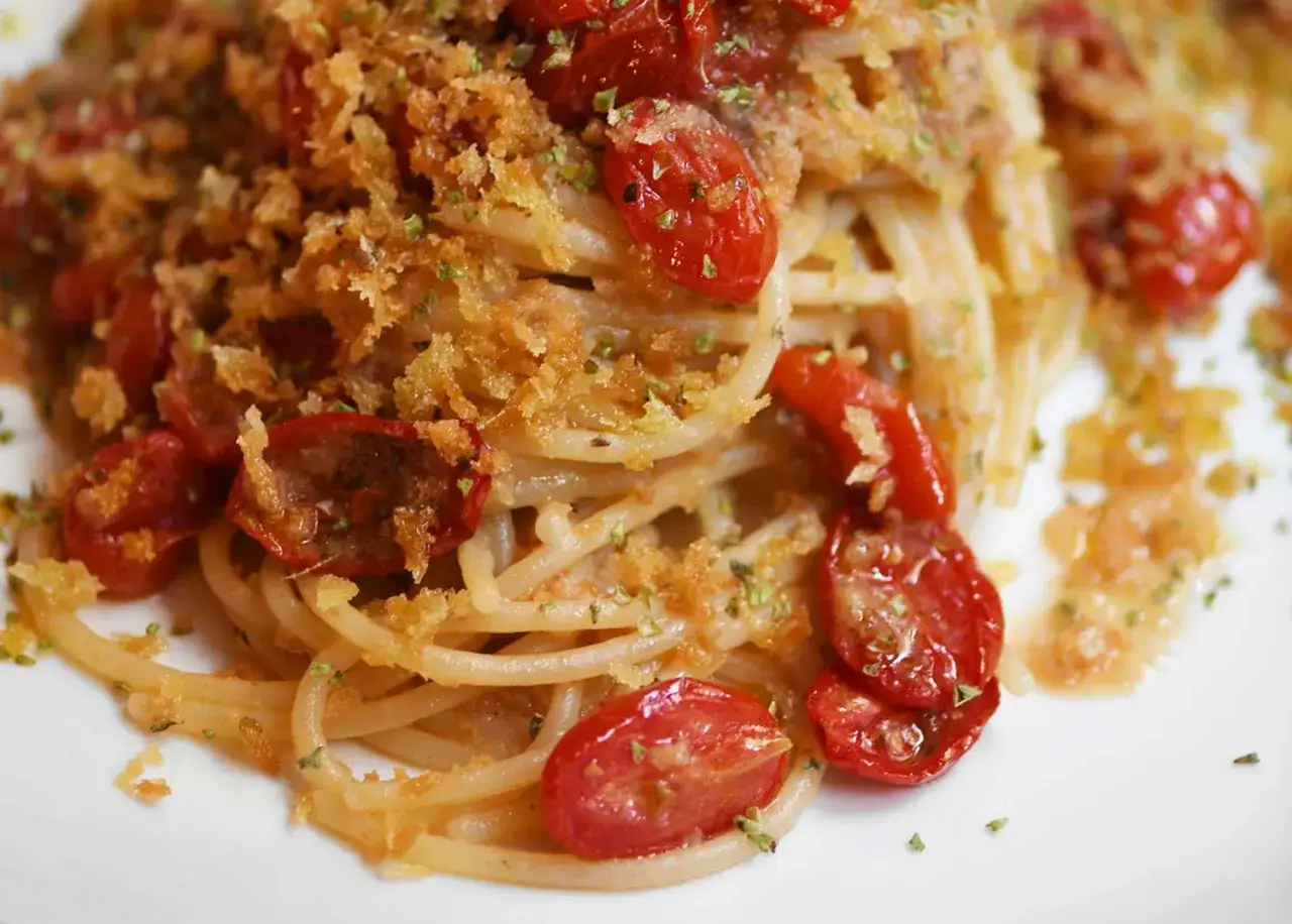 Spaghetti alla ghigliottina con pomodorini confit e mollica tostata, un piatto che fa venire l'acquolina in bocca.