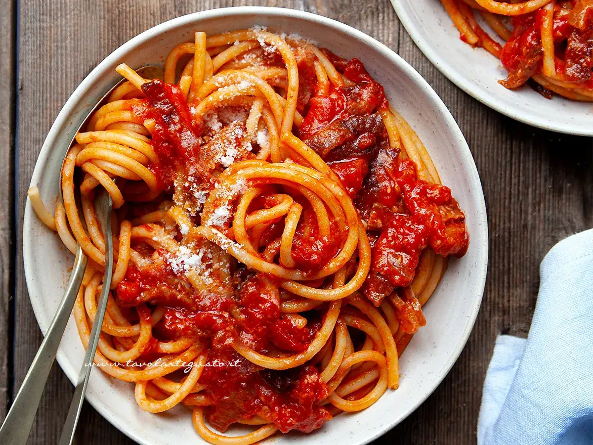 Un piatto fumante di spaghetti con sugo all'amatriciana ricetta della nonna, condito con guanciale croccante e pecorino grattugiato.