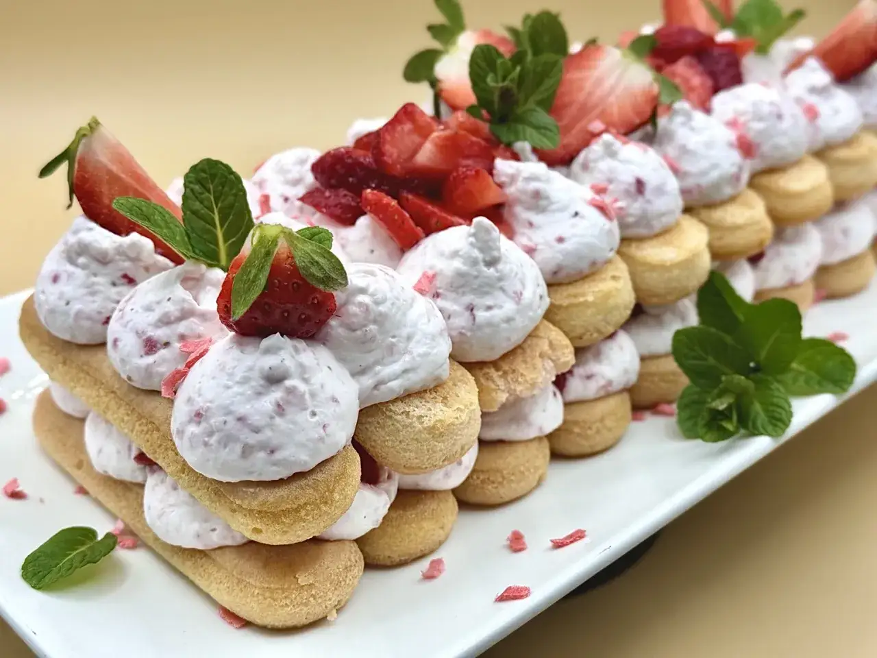 Delizioso tiramisù alle fragole, stratificato con savoiardi, crema soffice e fragole fresche, guarnito con menta.