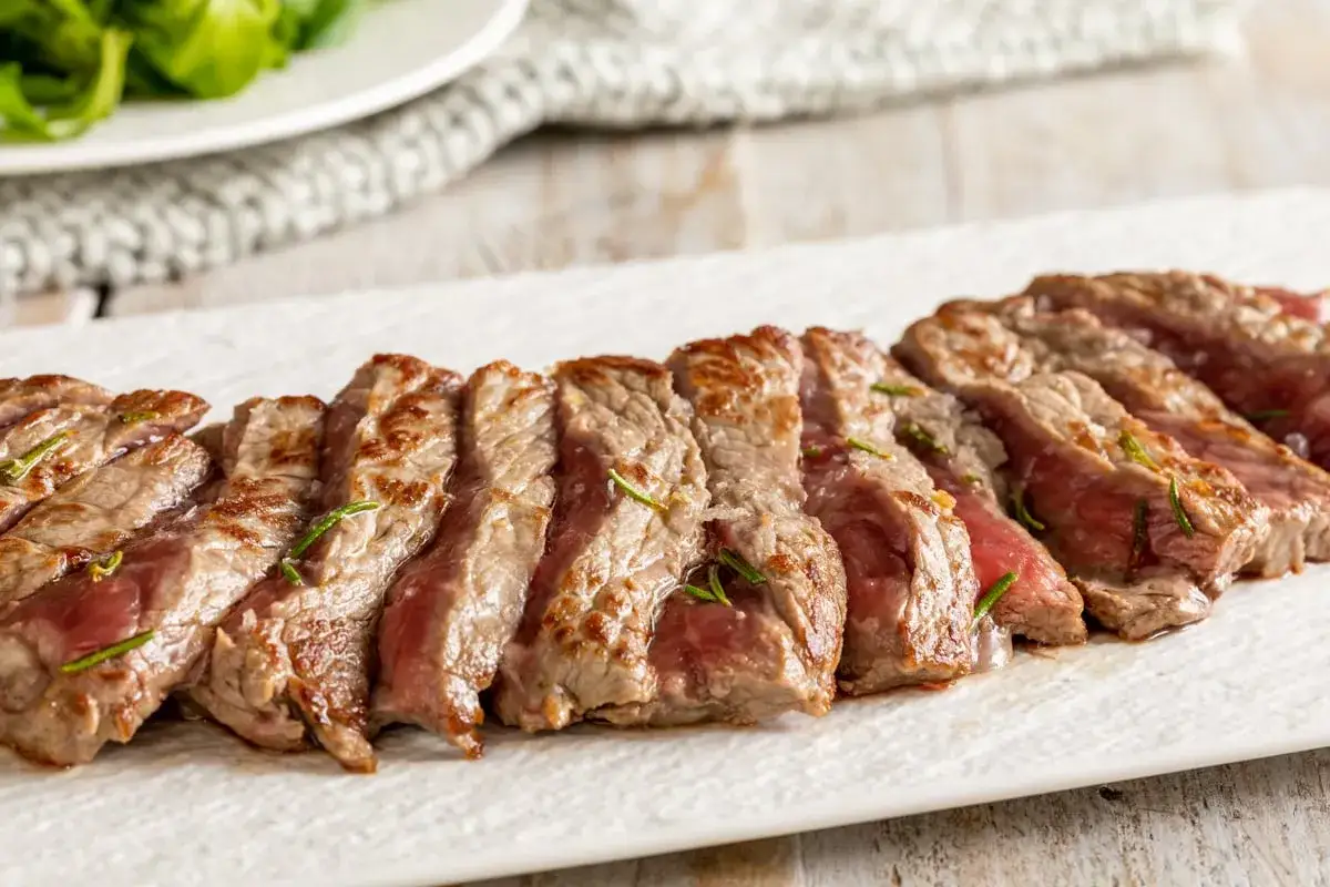 Una succulenta tagliata di manzo, affettata e guarnita con rosmarino, pronta per essere gustata.